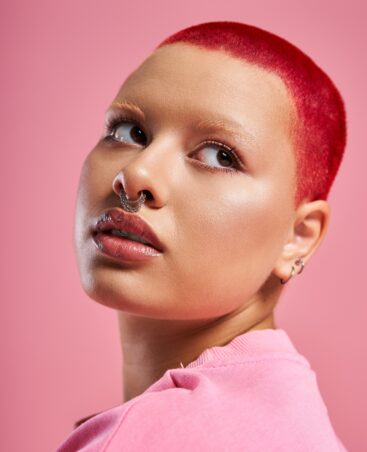 confident-young-woman-with-short-pink-hair-and-a-nose-piercing-in-a-vibrant-studio
