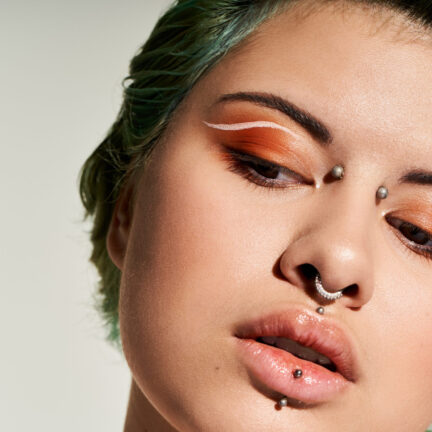 A confident young woman displays bold makeup and a unique fashion style, emanating vibrant energy.